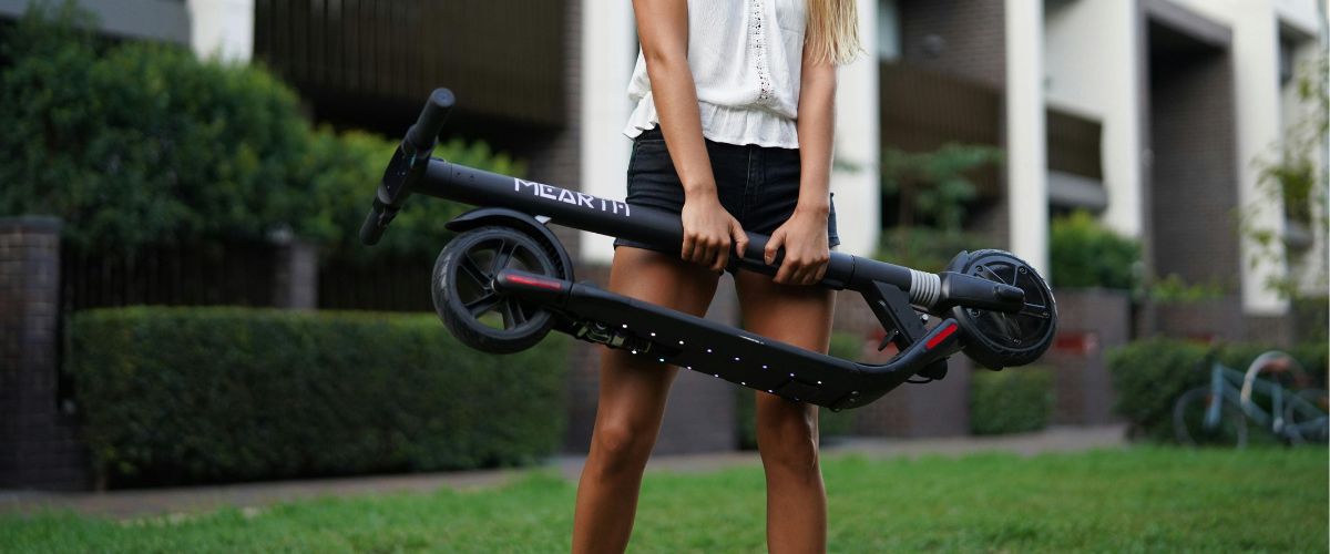 Photo d'une femme qui porte une trottinette électrique