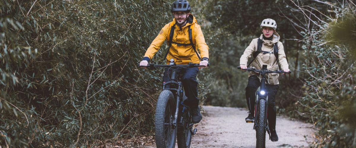 Deux personnes sur un vélo électrique en ballade en forêt