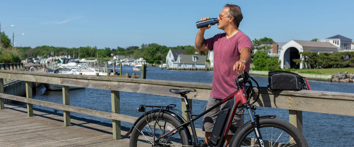 Homme avec son vélo électrique qui boit dans sa gourde pour s'hydrater