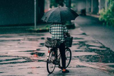 Personne à vélo sous la pluie avec parapluie
